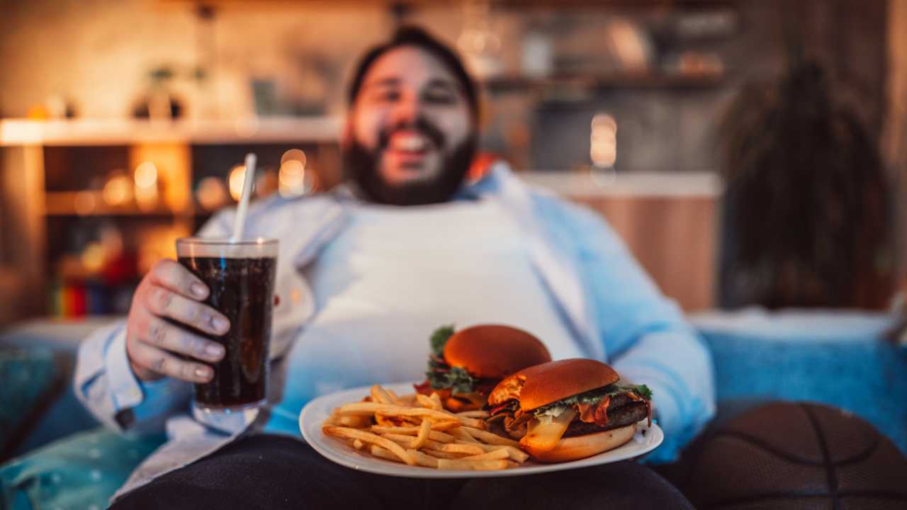 Un uomo obeso che mangia cibo spazzatura