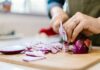 Una persona che affetta una cipolla rossa