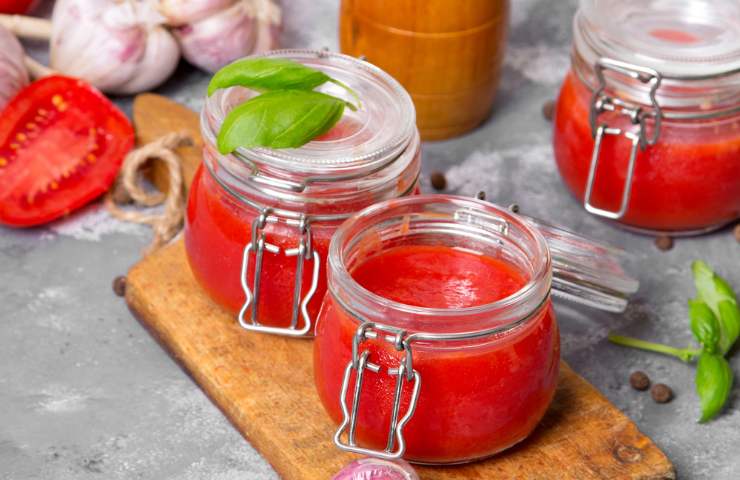 Barattoli con passata di pomodoro su un tagliere