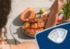 Una persona che mangia in vacanza ed una bilancia