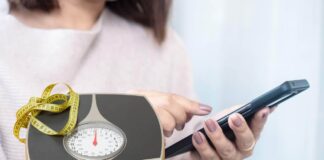 Una donna che consulta ChatGPT ed un metro ed una bilancia per la dieta