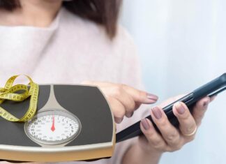 Una donna che consulta ChatGPT ed un metro ed una bilancia per la dieta