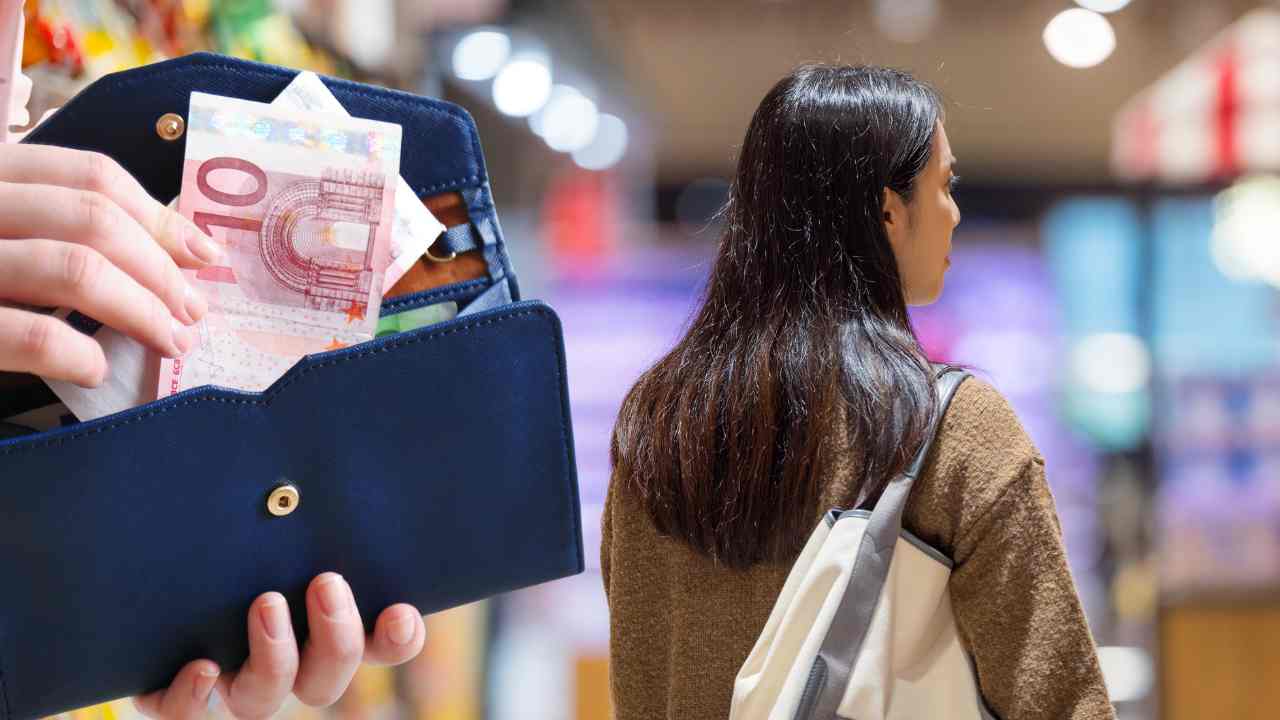 Una donna che fa la spesa e dei soldi in euro