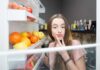 Una donna perplessa davanti al frigo aperto