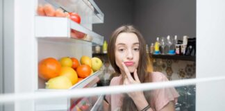 Una donna perplessa davanti al frigo aperto