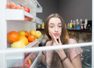 Una donna perplessa davanti al frigo aperto