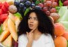 Diversi tipi di frutta estiva ed una donna perplessa
