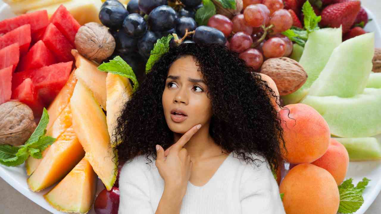 Diversi tipi di frutta estiva ed una donna perplessa