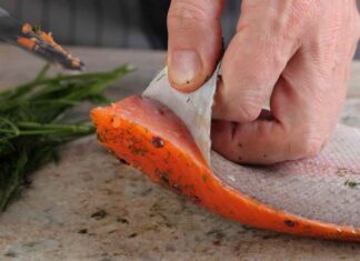 Pulizia di un filetto di salmone dalla sua pelle in corso