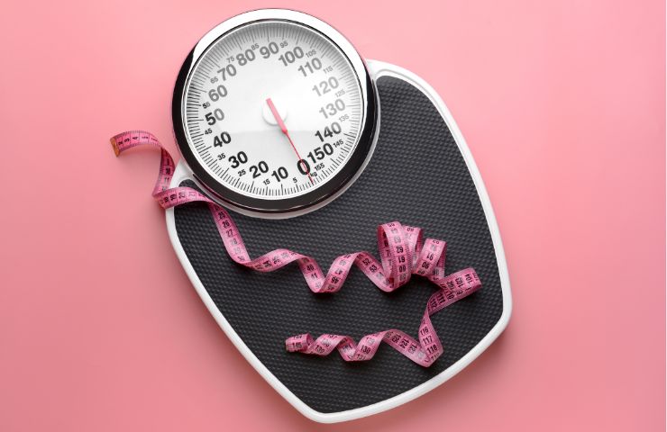 Bilancia e metro su sfondo rosa