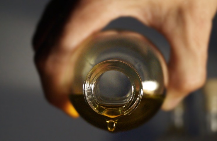 Mano che tiene una bottiglia di olio