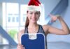 Il trucco che sto usando per non ingrassare prima di Natale (e funziona davvero) Ragazza sorridente con cappello di Babbo Natale ed una bilancia