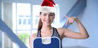 Ragazza sorridente con cappello di Babbo Natale ed una bilancia