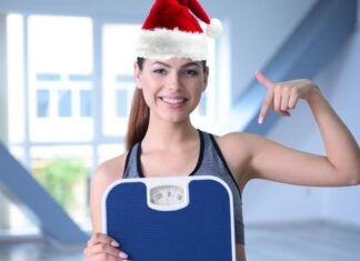 Ragazza sorridente con cappello di Babbo Natale ed una bilancia