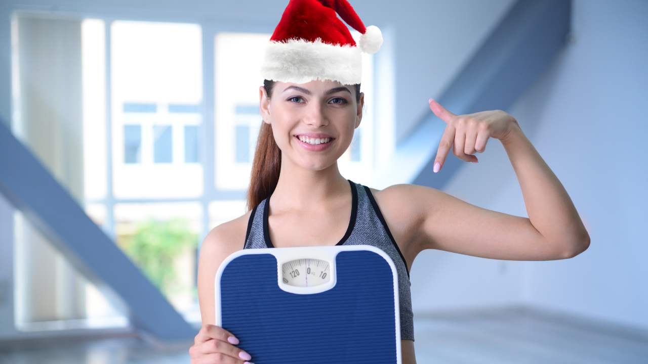 Ragazza sorridente con cappello di Babbo Natale ed una bilancia