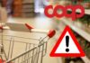 Carrello della spesa in supermercato con logo Coop e segnale di pericolo