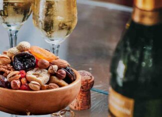 Occhio a cosa mangi e bevi a Natale, i prodotti più contaminati Calici con Prosecco e frutta secca su un tavolo