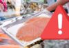 Salmone affumicato confezionato con segnale di pericolo e supermercato sullo sfondo