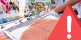 Salmone affumicato confezionato con segnale di pericolo e supermercato sullo sfondo